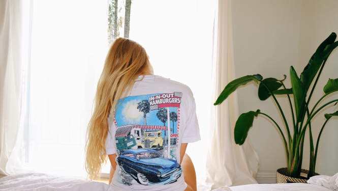 Foto: Meitene sēž uz gultas ar skatu uz logu