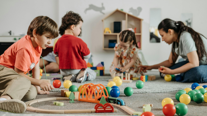 Pirmsskolas izglītības iestādes bērni rotaļājas kopā ar audzinātāju 