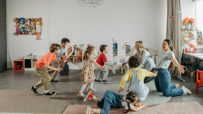 Priecīgi bērni rotaļājas kopā ar savām audzinātājām