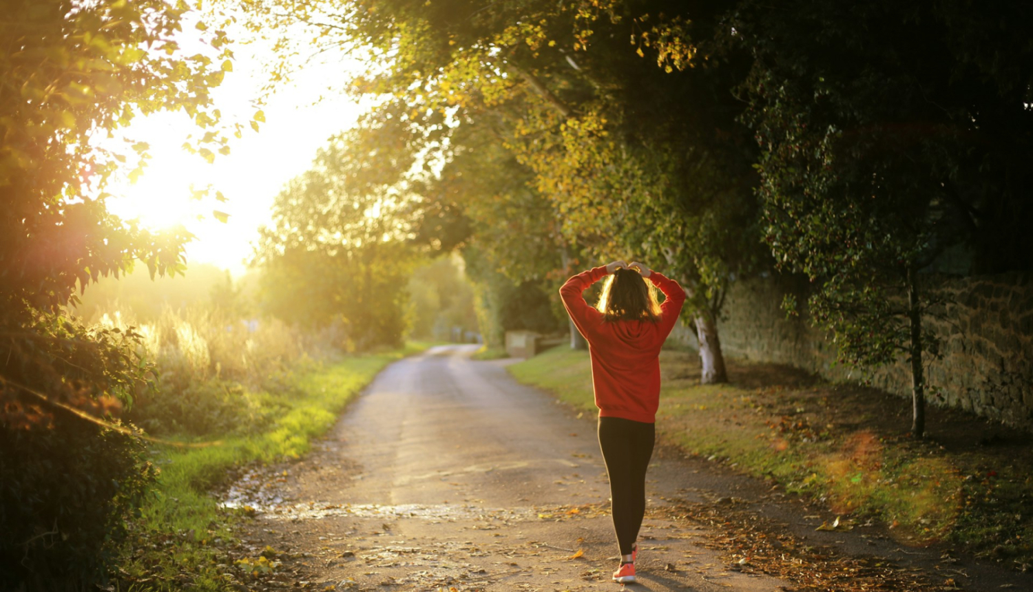 Meža ceļš uz kura atrodas sieviete un skatās uz saulrietu 