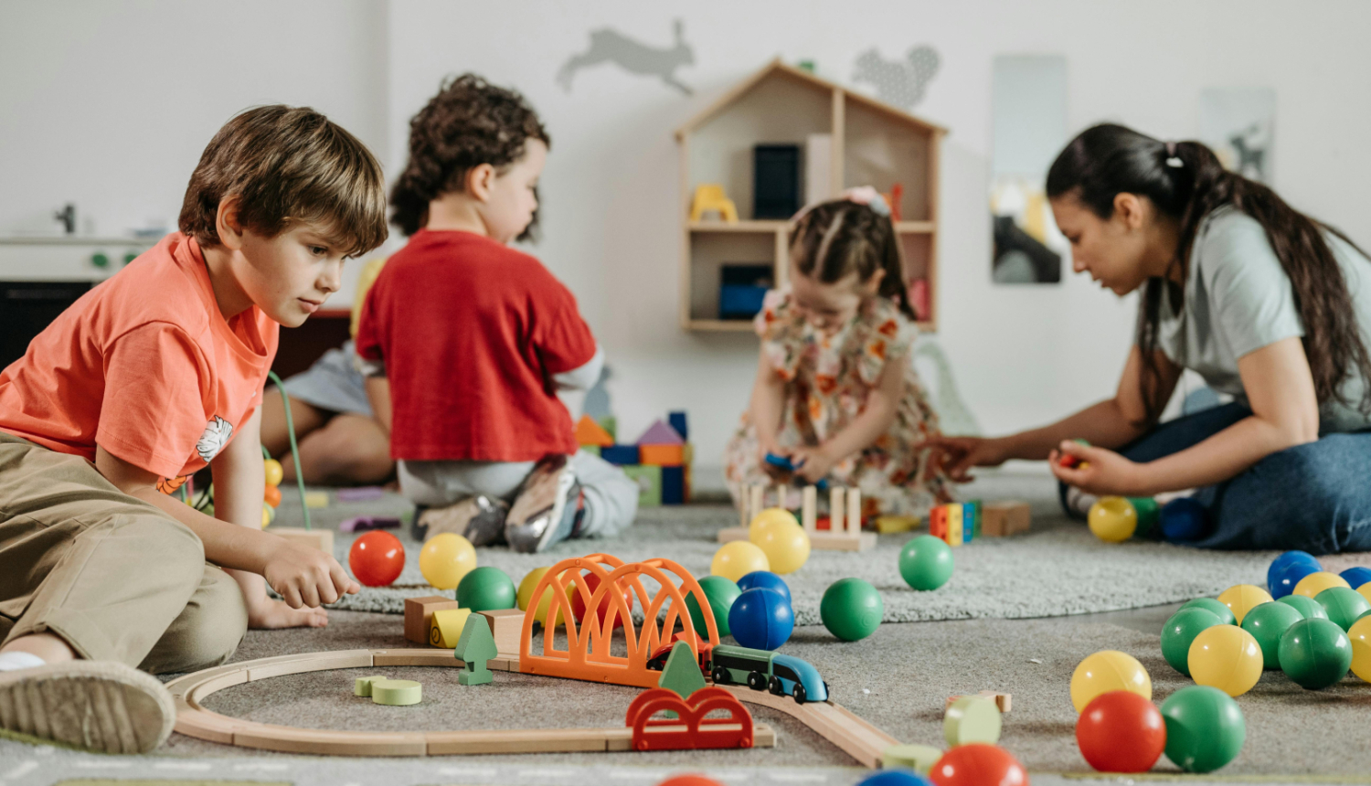 Pirmsskolas izglītības iestādes bērni rotaļājas kopā ar audzinātāju 